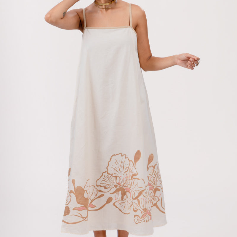 Woman wearing a white dress with floral embroidery on a white background