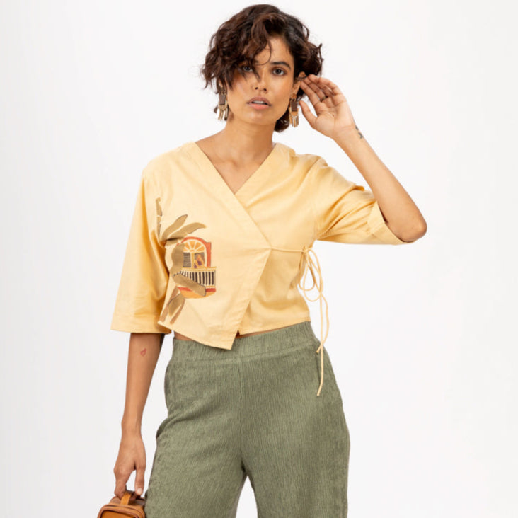 Woman wearing a yellow top and green pants with a white background