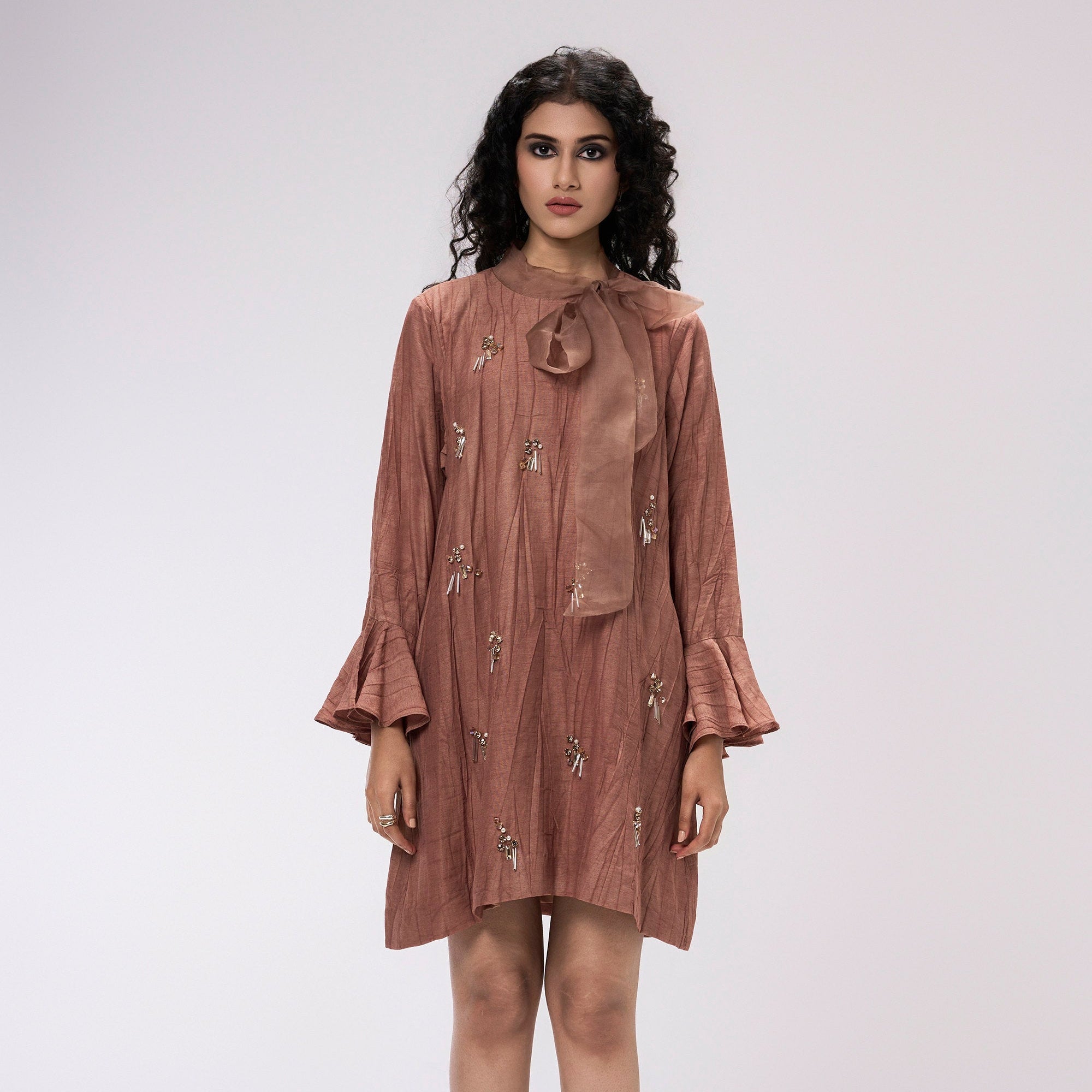 Woman wearing a brown dress with floral embroidery on a white background