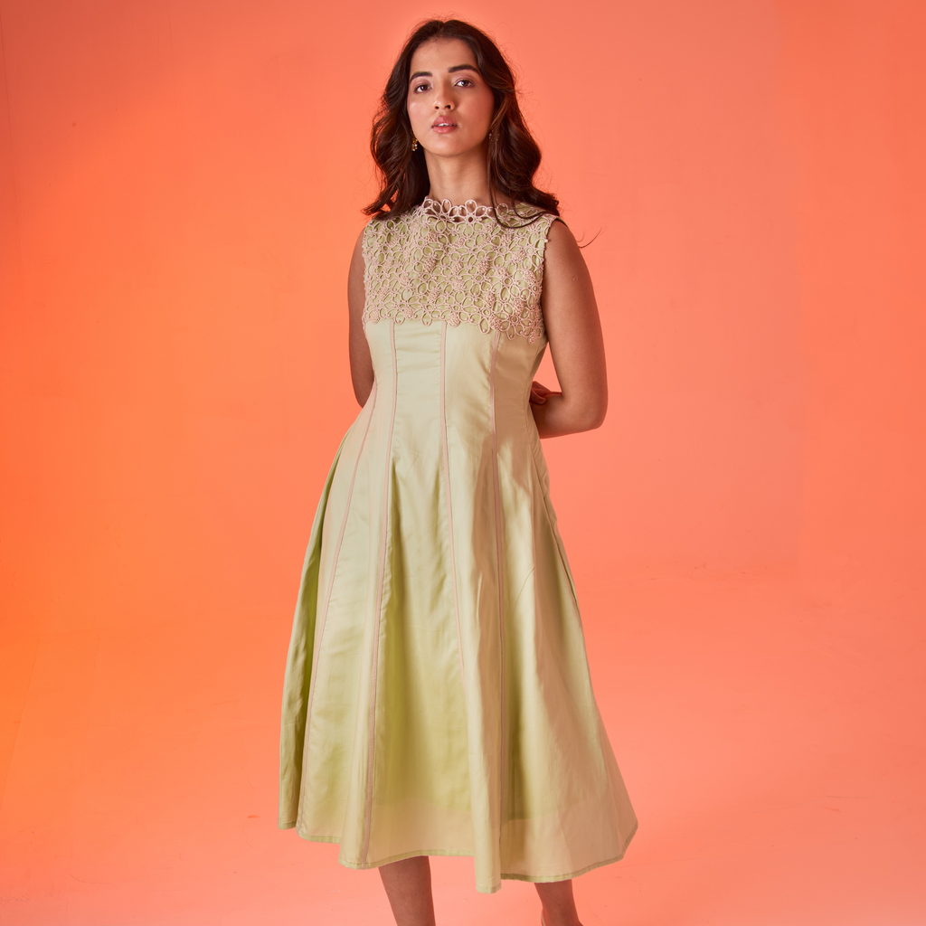 Woman wearing a light green dress with lace details against an orange background