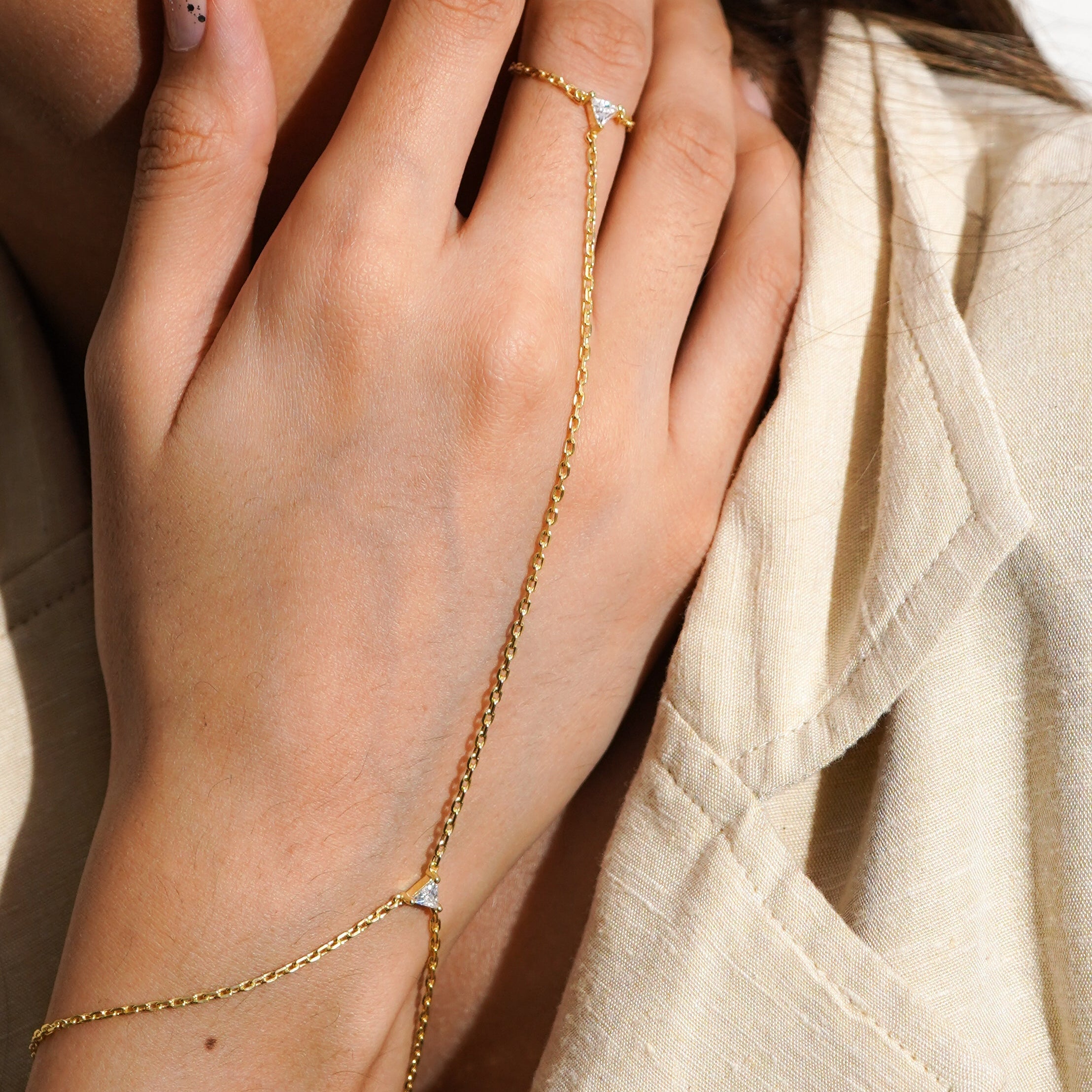 Close-up of a hand wearing a gold bracelet and ring with small diamonds.