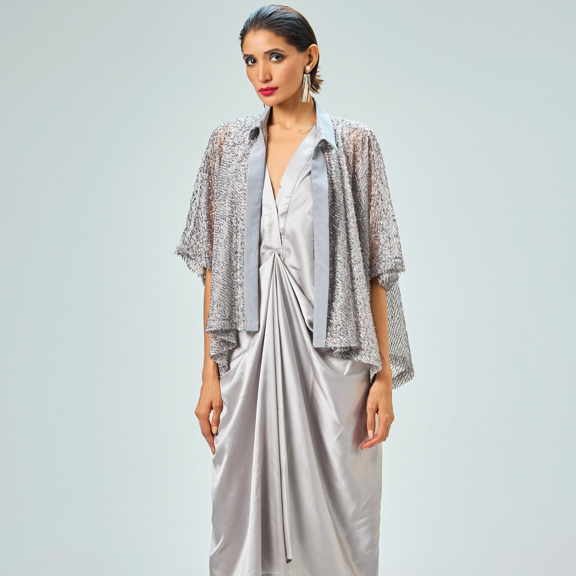 Woman wearing a silver outfit with a jacket and skirt on a white background