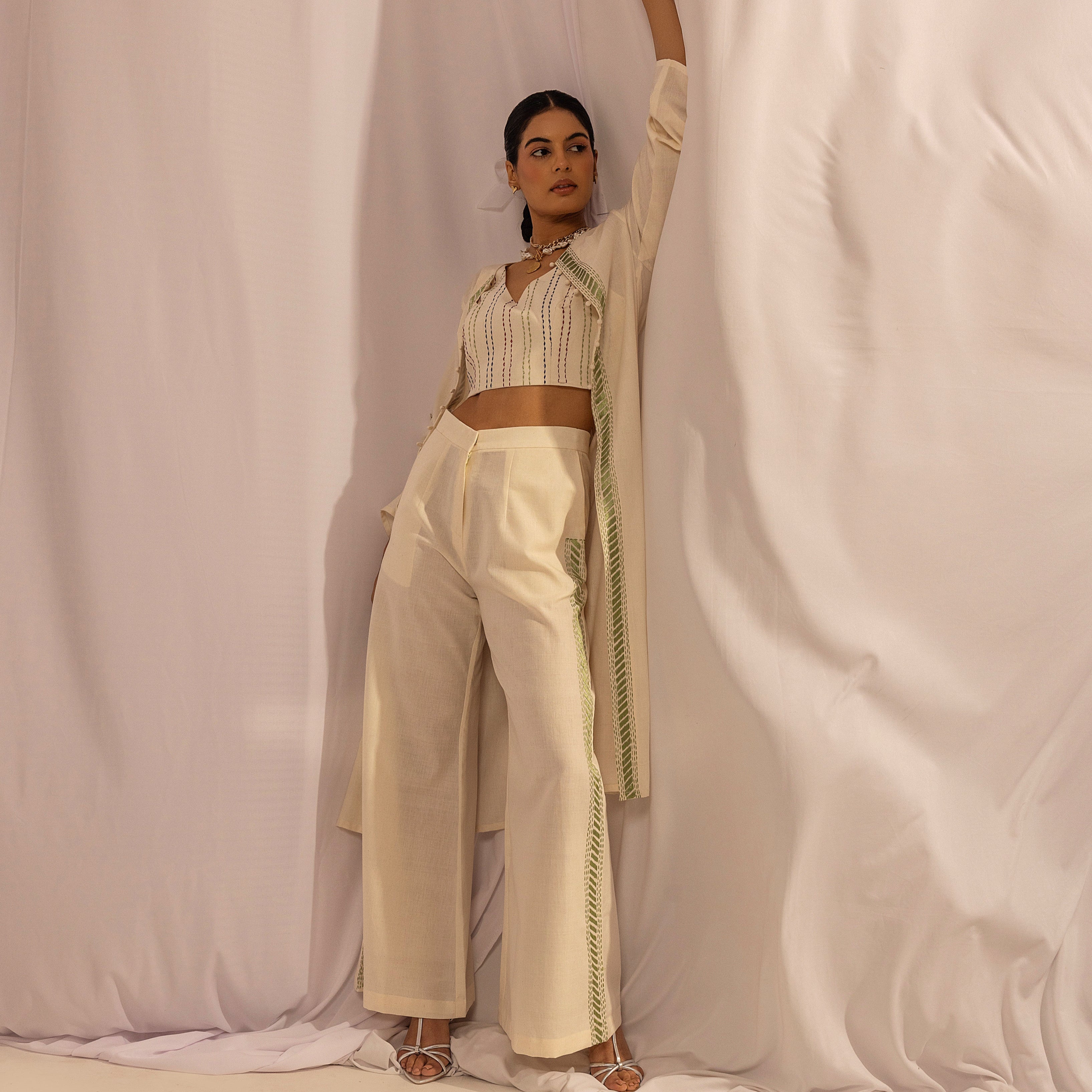 Woman in a beige outfit standing against a white curtain
